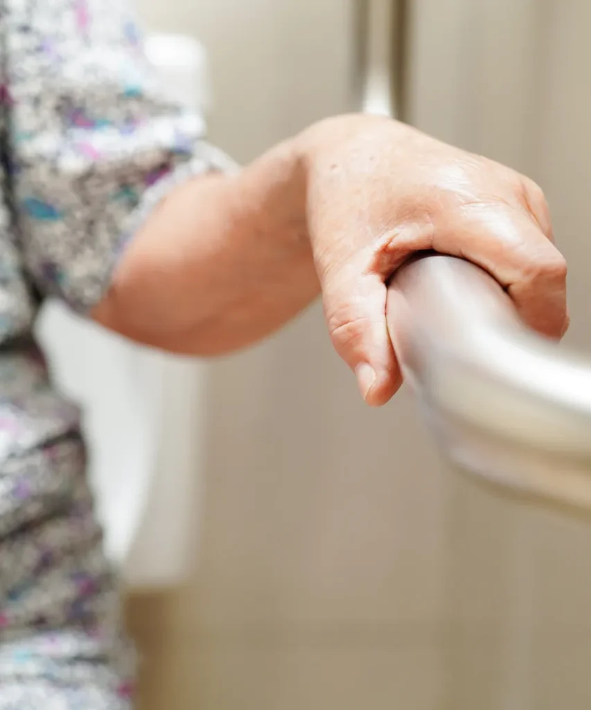 Seniorenhand hält sich an einem stabilen Haltegriff im Badezimmer fest, Fokus auf Unterstützung und Sicherheit im Alltag