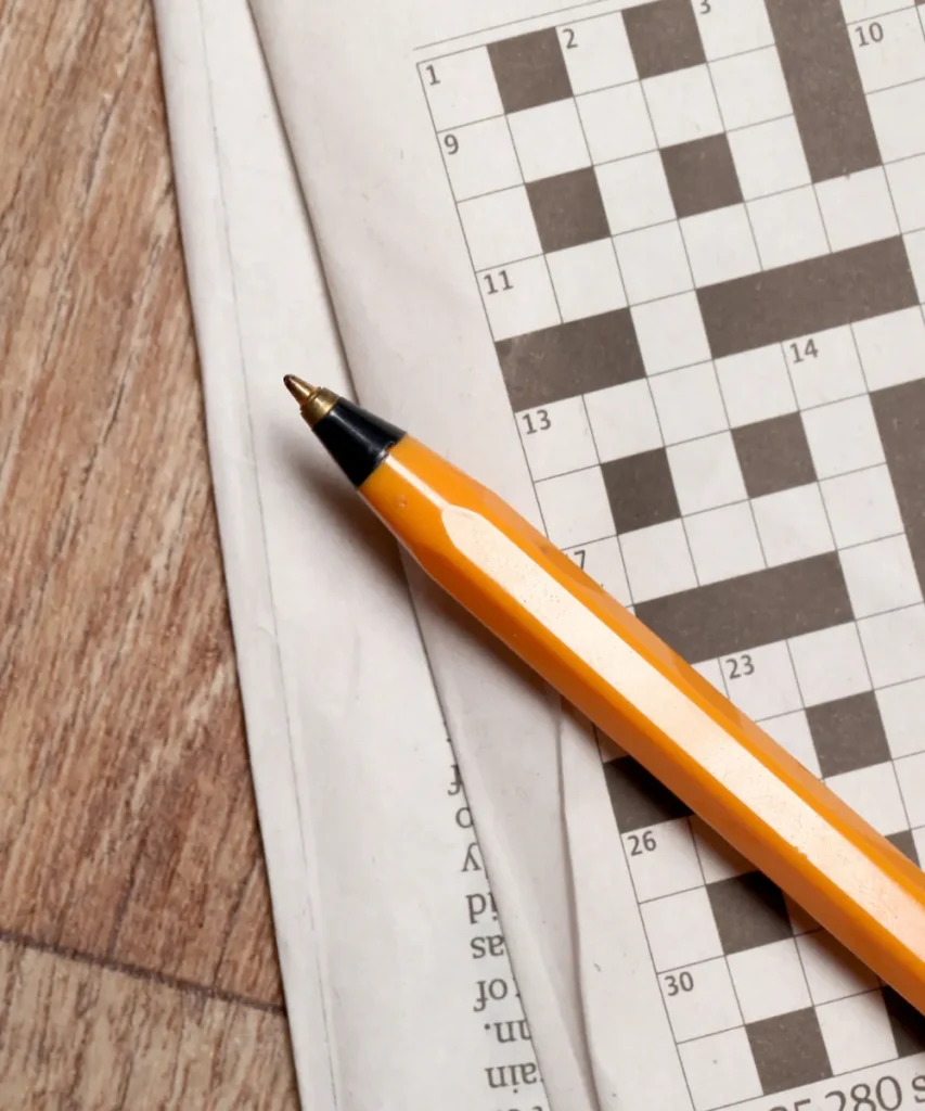 Gelber Kugelschreiber liegt auf Zeitung mit Kreuzworträtsel – Gedächtnisverlust vorbeugen mit Gedächtnistraining