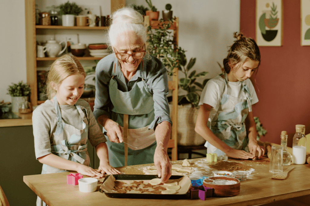Ältere Frau backt mit zwei Kindern in der Küche – gemeinsame demenzfreundliche Aktivität