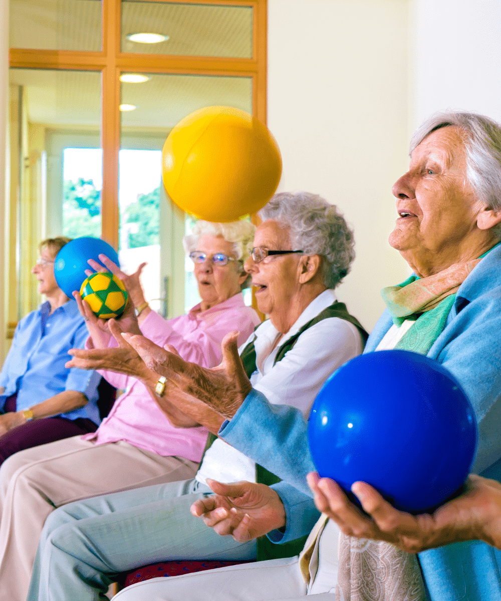Gruppe älterer Menschen bei Ballübung im Sitzen – leichte Bewegung als demenzfreundliche Aktivität