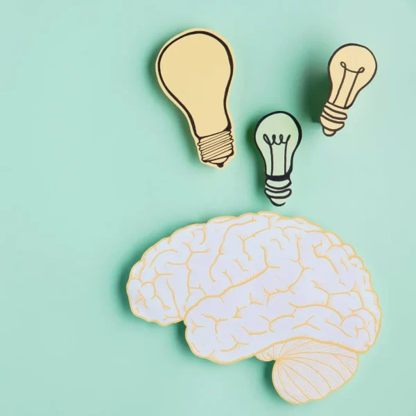 Weiße Gehirnillustration mit drei bunten Glühbirnen auf türkisfarbenem Hintergrund, symbolisiert Ideenfindung und Denkanreize